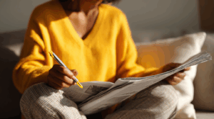 An woman adult sitting comfortably with a newspaper and a highlighter