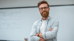 A confident teacher standing in front of a whiteboard in a classroom