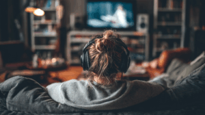 A person relaxing with headphones on while watching an English show