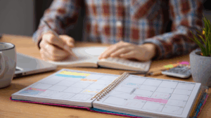 A person sitting at a desk with a calendar and a planner
