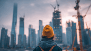 A person standing in front of a city skyline, observing the modern developments around them.