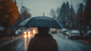 A man walking through a rainy street with an umbrella