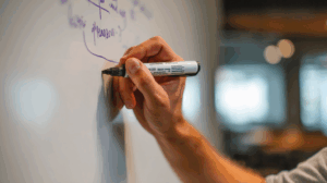 A person writing 'will' on a whiteboard