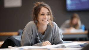 A student sitting at a desk, smiling confidently as they review their grammar notes