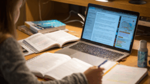A student sitting at a desk surrounded by a notebook, a grammar book