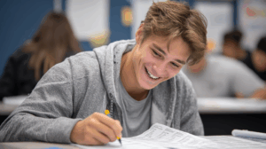 A student smiling and reviewing a completed grammar worksheet