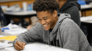 A student smiling while reviewing a grammar worksheet 