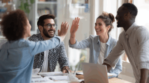 A team at the office celebrating with high-fives and a 'Project Completed'