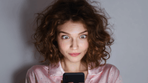 A woman looking at her phone with a curious expression