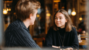 Two young adult professionals talking in a café