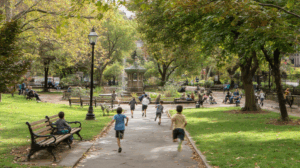  A lively park scene with children running and playing while adults are sitting on nearby benches