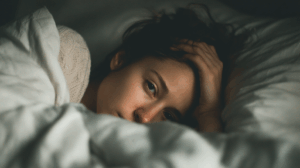 A person lying in bed, looking tired and frustrated