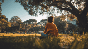 A person sitting in a park, reflecting on their progress with learning English