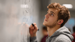 A student looking at a whiteboard with two sentences