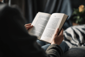A person sitting comfortably reading a printed essay or manuscript aloud