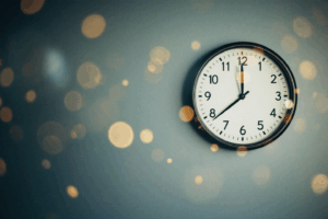 A clock on the wall, with hands ticking towards a specific time.