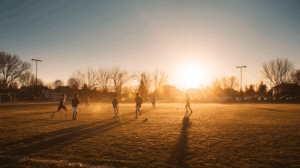 A group of friends actively playing football on a sunny field