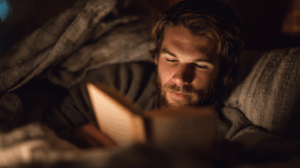a man young adult reading a book before sleeping