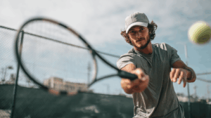 a young adult man playing tennis